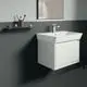 Moderne Badezimmeransicht mit Waschbecken, Unterbau und einer Wandablage. Ideal Standard-Armatur über dem Waschbecken. Graue und helle Wände schaffen einen minimalistischen Look.
